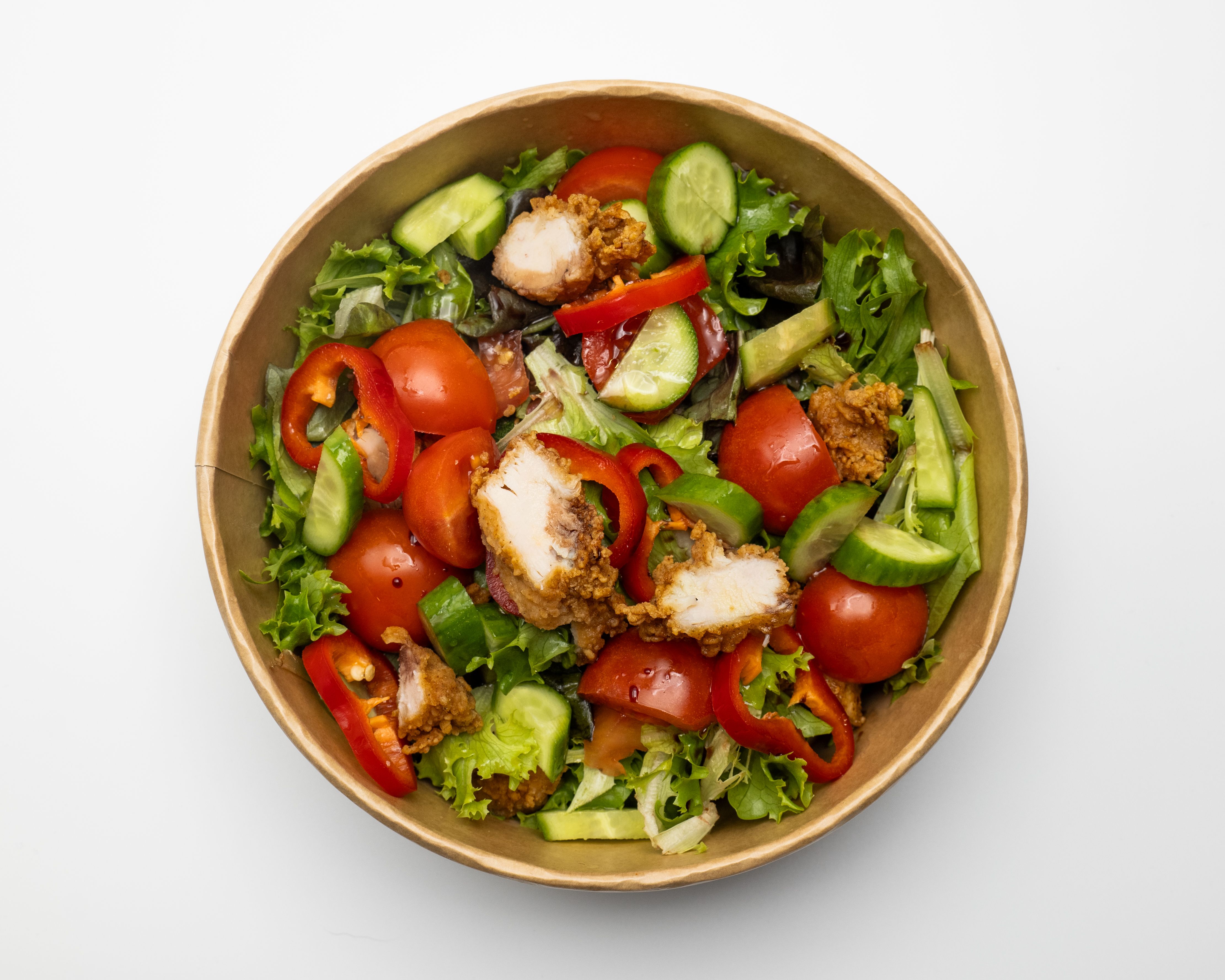 Colorful crispy chicken garden salad in a kraft takeout bowl